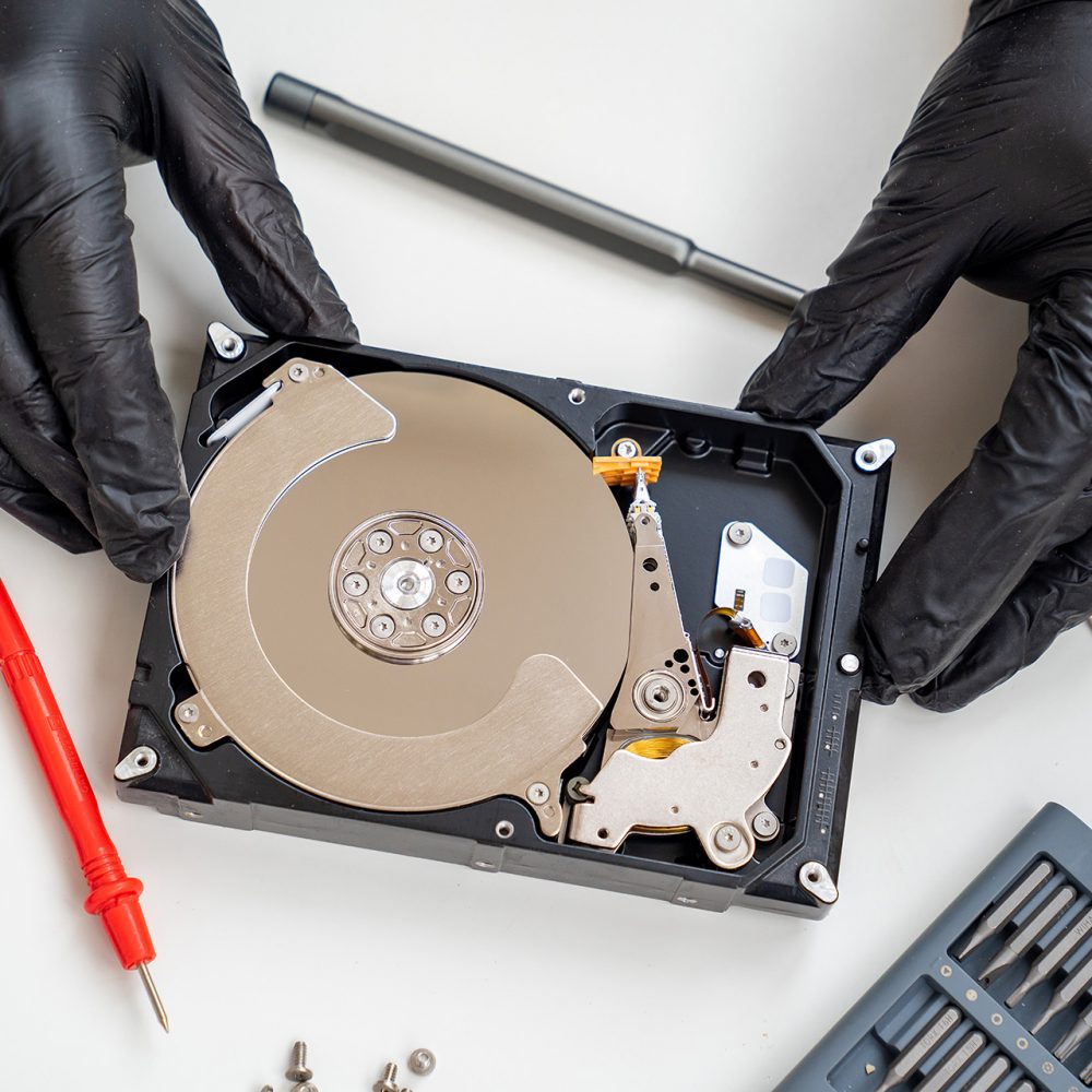 open Computer Hard Drive on white background with screwdriver set. Hands in black gloves. master of repair.