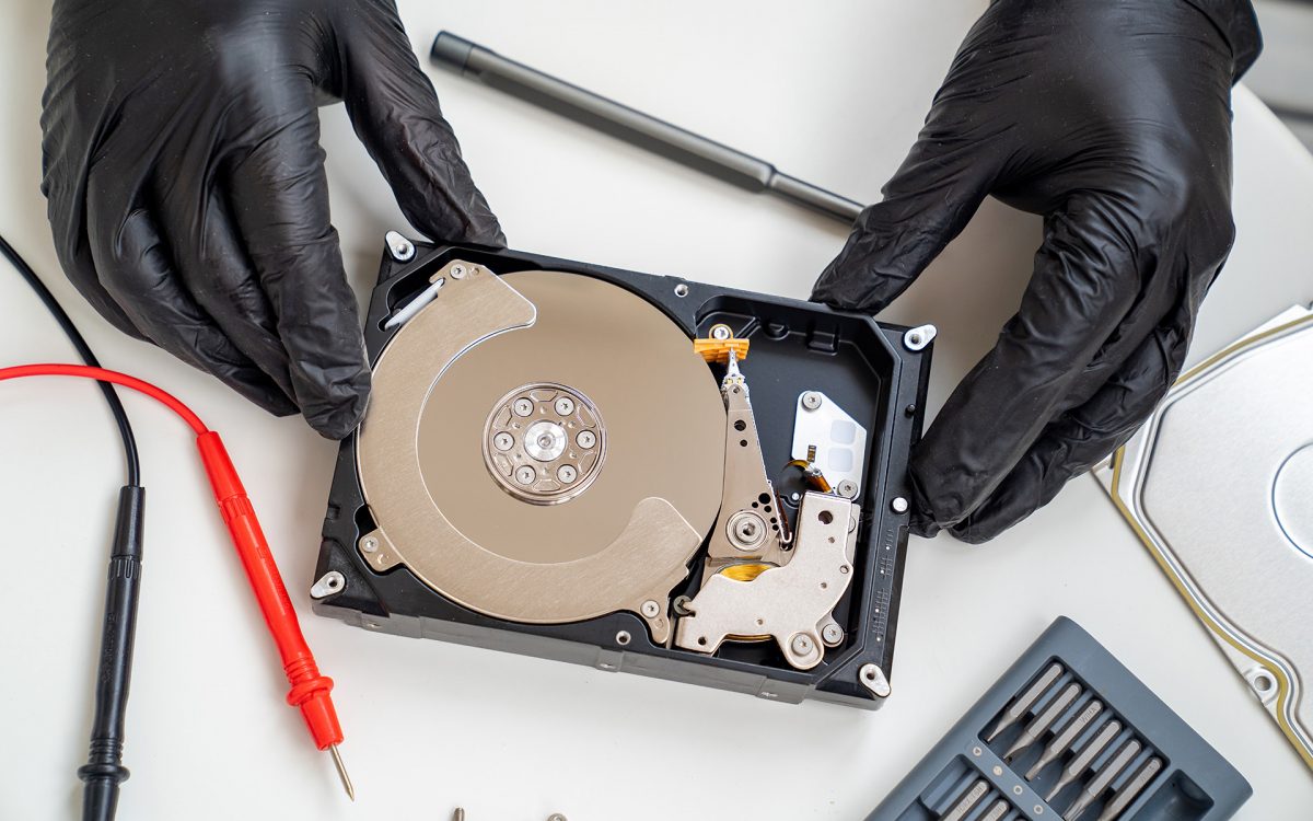 open Computer Hard Drive on white background with screwdriver set. Hands in black gloves. master of repair.
