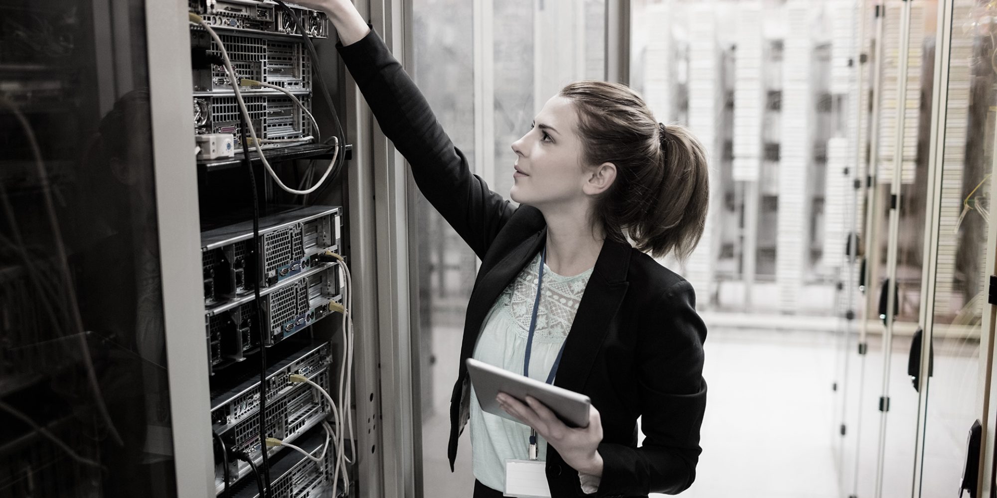Technician holding digital tablet while examining server in server room